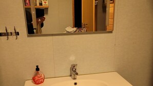 A bathroom with a white sink, a mirror, a toilet, and a cabinet with drawers.