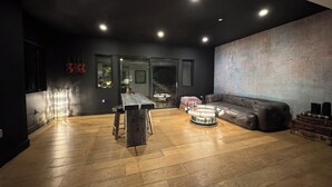 Una sala de estar moderna con una pared oscura, piso de madera, un sofá de cuero y una mesa de centro redonda.