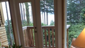 Un salon chaleureux avec une table basse en bois, un canapé et une vue sur une forêt, visible à travers une porte vitrée.