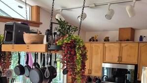 A modern kitchen with a central island, hanging pots, and bar stools. - SeaView Getaway- B.L.T. (bed and local treats), Retreat. (Sechelt)