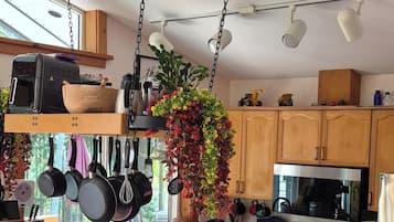 A modern kitchen with a central island, hanging pots, and bar stools.