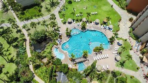 Ein großer Pool, umgeben von Palmen und Liegestühlen, mit einem steinernen Weg, der zum Pool führt.