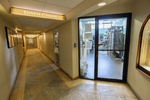A hallway leading to a fitness center with a sign overhead, a glass door entrance, and a tiled floor. - Kaanapali Shores | Ocean View 7 BR, Sleeps 22 | Car Incl. w/ 6+ Nights | KS ML-3771 by KBM (Lahaina)