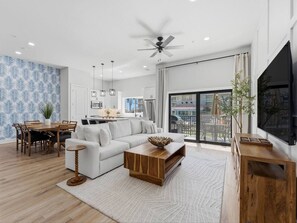 Ein modernes Wohnzimmer mit Sofa, Couchtisch, Esstisch und Fernseher.