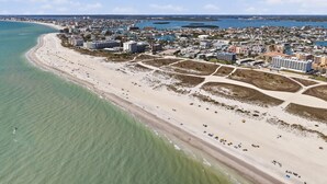 An aerial view of a coastal city with a wide beach, clear skies, and a mix of residential and commercial buildings. - Capri-Lux Pool/Hot-Tub/Steps To the Beach (Treasure Island)