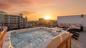 A rooftop hot tub with a sunset view, a lounge area with a sofa, and a poolside deck. - Capri-Lux Pool/Hot-Tub/Steps To the Beach (Treasure Island)