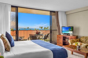 Ein Hotelzimmer mit Bett, Fernseher, Balkon mit Meerblick und Essbereich.