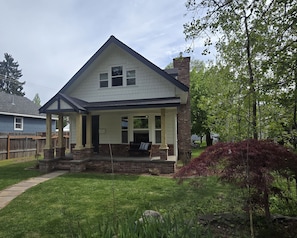 A two-story house with a covered porch, a brick chimney, and a well-maintained lawn.