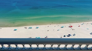 A beach with clear water, a sandy shore, and umbrellas.