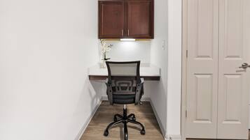 Een kleine kantoorruimte met een bureau, stoel en een kast erboven.