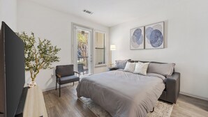 A bedroom with a bed, a chair, a TV, and a plant. - Modern Styled  1 King+Sofa Bed Retreat Frisco, TX (Frisco)