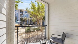 A balcony with a metal railing, a chair, and a table. - Modern Styled  1 King+Sofa Bed Retreat Frisco, TX (Frisco)