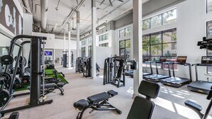 A spacious gym with various exercise equipment, large windows, and a ceiling fan. - Modern Styled  1 King+Sofa Bed Retreat Frisco, TX (Frisco)