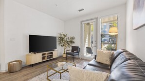 A modern living room with a flat-screen TV, leather sofa, and a potted plant. - Modern Styled  1 King+Sofa Bed Retreat Frisco, TX (Frisco)