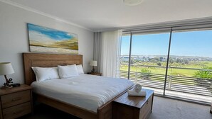 Een hotelkamer met een groot bed, nachtkastje, raam met uitzicht op de omgeving en een plafondlamp.