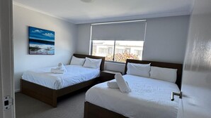 Een hotelkamer met twee bedden, een schilderij aan de muur en een raam met uitzicht.