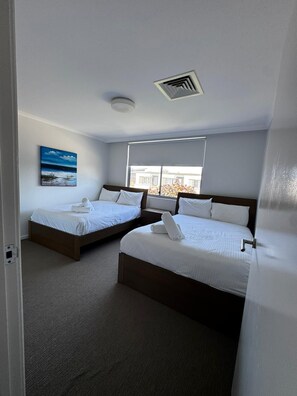 A hotel room with two beds, a painting on the wall, and a window with a view. - Fairway Retreat (Magenta)