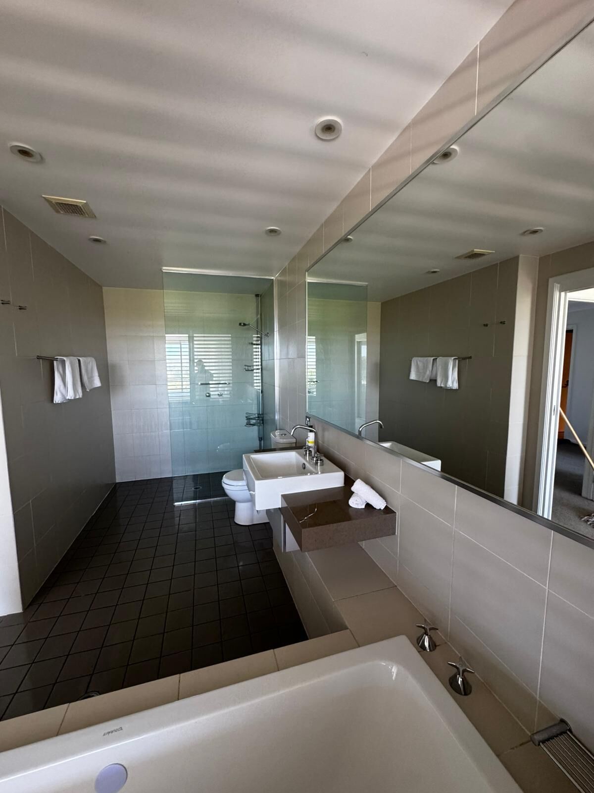 Et moderne badeværelse med et stort badekar, et separat bruseområde og en vaskepult med et spejl.