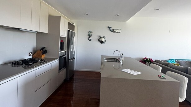 Een moderne keuken met witte kasten, een centraal eiland en een zithoek met een bank.