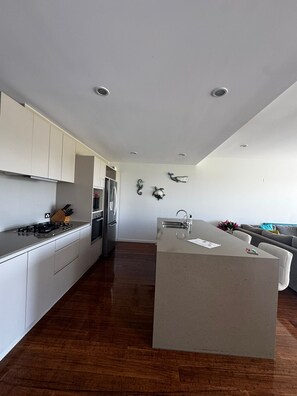 Een moderne keuken met witte kasten, een centraal eiland en een zithoek met een bank.