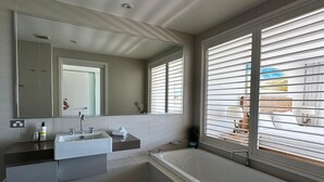 Een moderne badkamer met een badkuip, een wastafel en een grote spiegel.