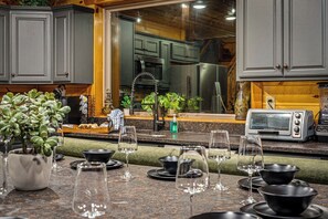 A kitchen with grey cabinets, a stainless steel refrigerator, a toaster, and a potted plant. - NEW! Pool! Ultra Luxe 4BR Cabin w/Theater (Gatlinburg)