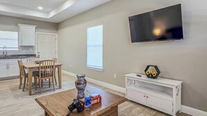 A modern living room with a ceiling fan, a flat-screen TV, a wooden coffee table, and a dining area with chairs and a table. - Welcoming 2-bedroom house with AC in charming Eagle Pass (Eagle Pass)