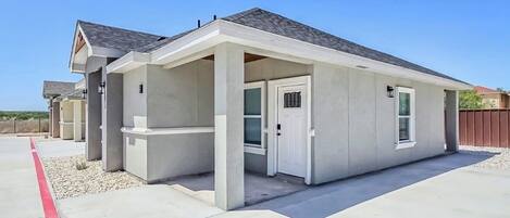 A single-story building with a flat roof, a covered porch, and a garage door.