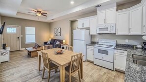 A modern kitchen with white cabinets, a granite countertop, and a dining area with a wooden table and chairs. - Welcoming 2-bedroom house with AC in charming Eagle Pass (Eagle Pass)