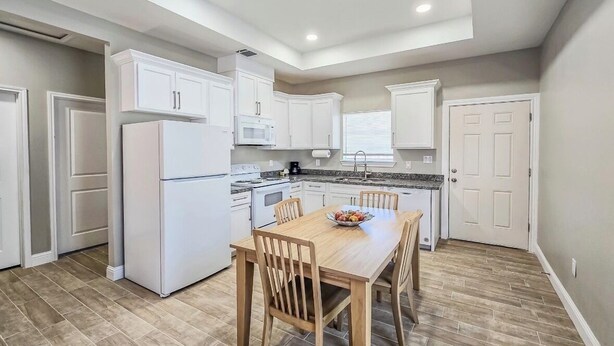 A modern kitchen with white cabinets, a wooden dining table, and a built-in oven. - Welcoming 2-bedroom house with AC in charming Eagle Pass (Eagle Pass)
