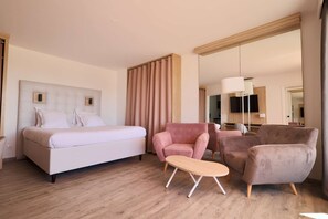 Una habitación de hotel con cama, dos sillones, una mesita y un espejo grande.