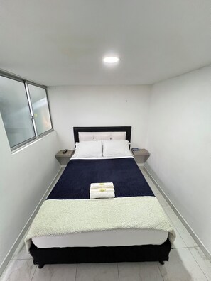 A single bed with a dark headboard, white bedding, and a bedside table with a lamp. - Modern apartment in Manizales | Excellent location + Wifi + High comfort (Manizales)