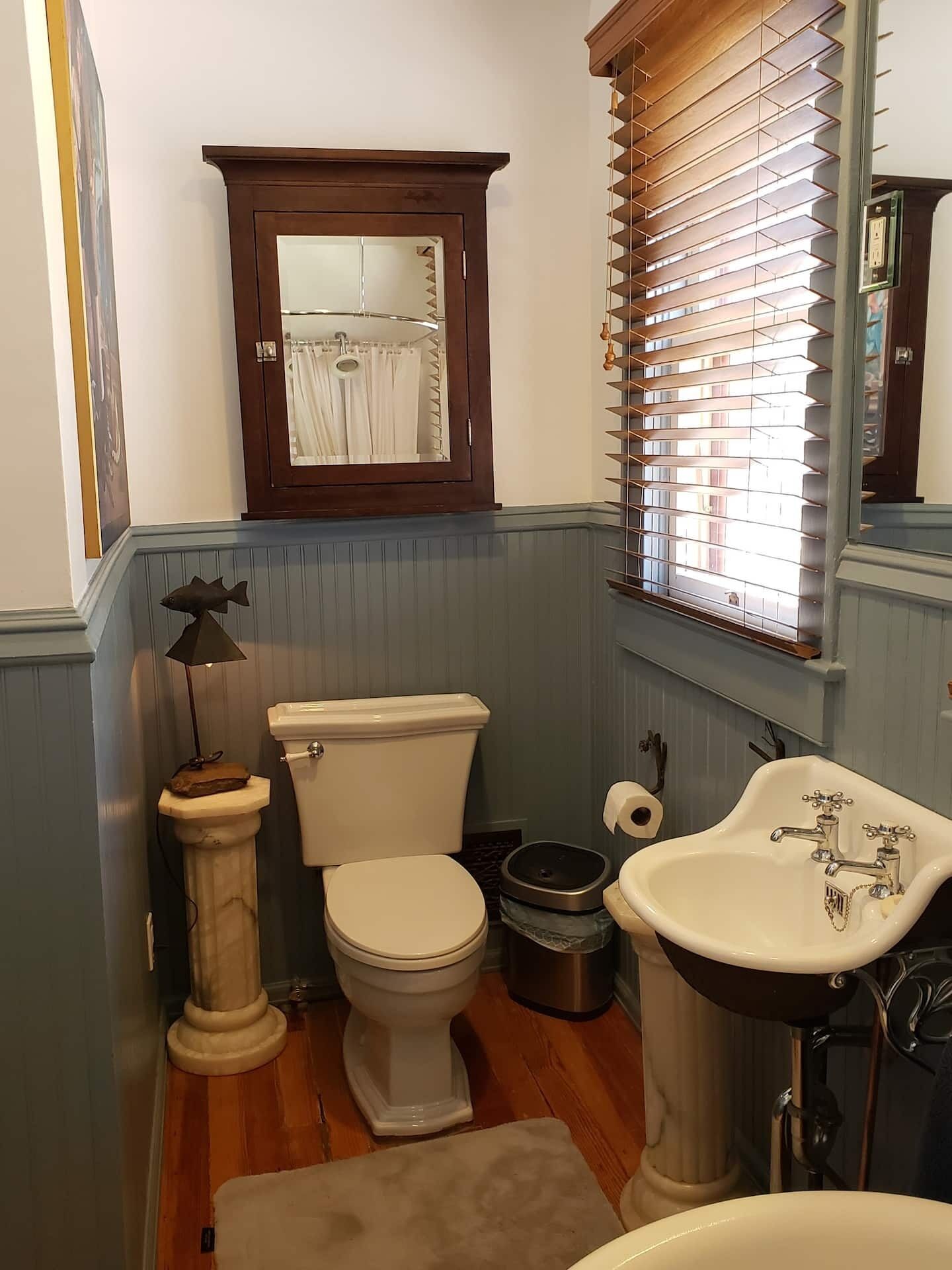 A bathroom with a toilet, bidet, sink, and wooden floor.