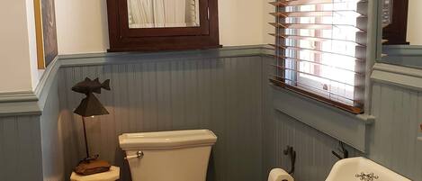 A bathroom with a toilet, bidet, sink, and wooden floor.