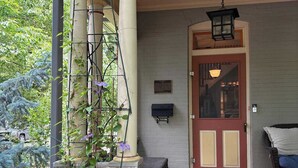 En byggnadsentré med siffran ’1017’ ovanför dörren, en brevlåda, en bänk och en välkomstmatta.