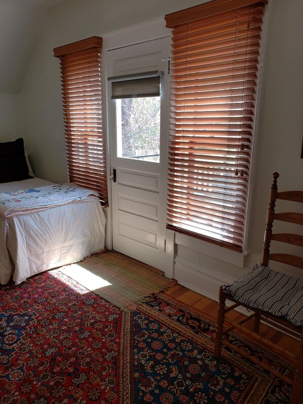 Une chambre à coucher avec un lit, une chaise, une porte avec une fenêtre et un tapis à motifs.