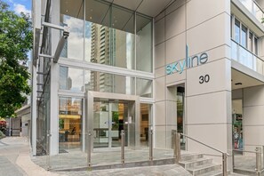 A modern building with a glass entrance, the name 'Skyline' on the facade, and the number '30' indicating its address. - Luxe 3BR Apt w/ River Views + Resort Amenitie (Brisbane)