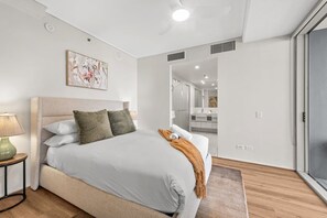 Un dormitori modern amb un llit gran, una taula de nit, una làmpada i un quadre a la paret.