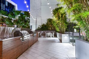 Un patio exterior con una parrilla, zona de estar y plantas en macetas.