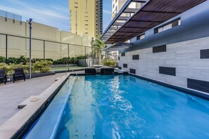 A swimming pool with a tiled deck, surrounded by a fence and greenery. - Luxe 3BR Apt w/ River Views + Resort Amenitie (Brisbane)