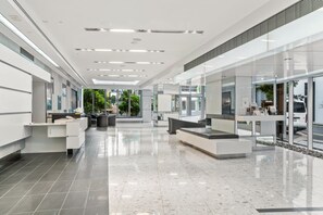 A spacious lobby with a reception desk, seating areas, and a glass wall providing a view of the outdoors. - Luxe 3BR Apt w/ River Views + Resort Amenitie (Brisbane)