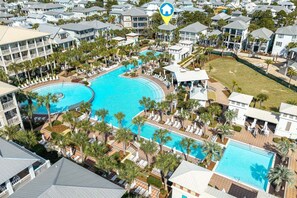Vue aérienne d’un complexe hôtelier doté de plusieurs piscines, de palmiers et de propriétés situées en bord de mer.