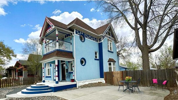 A two-story house with a balcony, a front porch, and a patio area with outdoor furniture. - Wonderful 2-bedroom house in Denver perfect for your getaway (Denver)