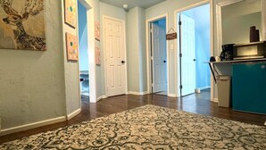 A hallway with a patterned rug, white doors, and a kitchen area with a blue refrigerator. - Wonderful 2-bedroom house in Denver perfect for your getaway (Denver)