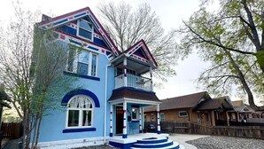 A two-story house with a porch, a small front yard, and a wooden fence. - Wonderful 2-bedroom house in Denver perfect for your getaway (Denver)