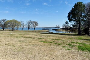 A grassy field with a body of water, trees, and a bridge. - RV SPACE FOR RENT (Alba)