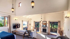 A spacious living room with a television, seating area, and a fireplace. - The Loft at Cypress Ridge Estate (Waiheke Island)