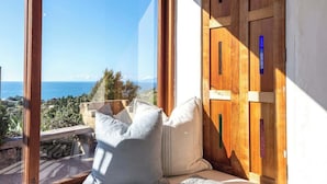 Ein Zimmer mit Meerblick, eine Holztür und ein Fenster mit Kissen.