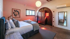 Un dormitorio con cama, mesita de noche, armario, ventana y espejo.