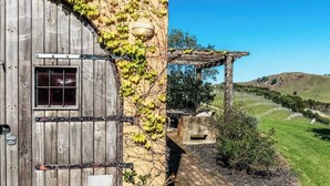 Un edificio rústico con una puerta de madera, una ventana y una pérgola con estructura de piedra.